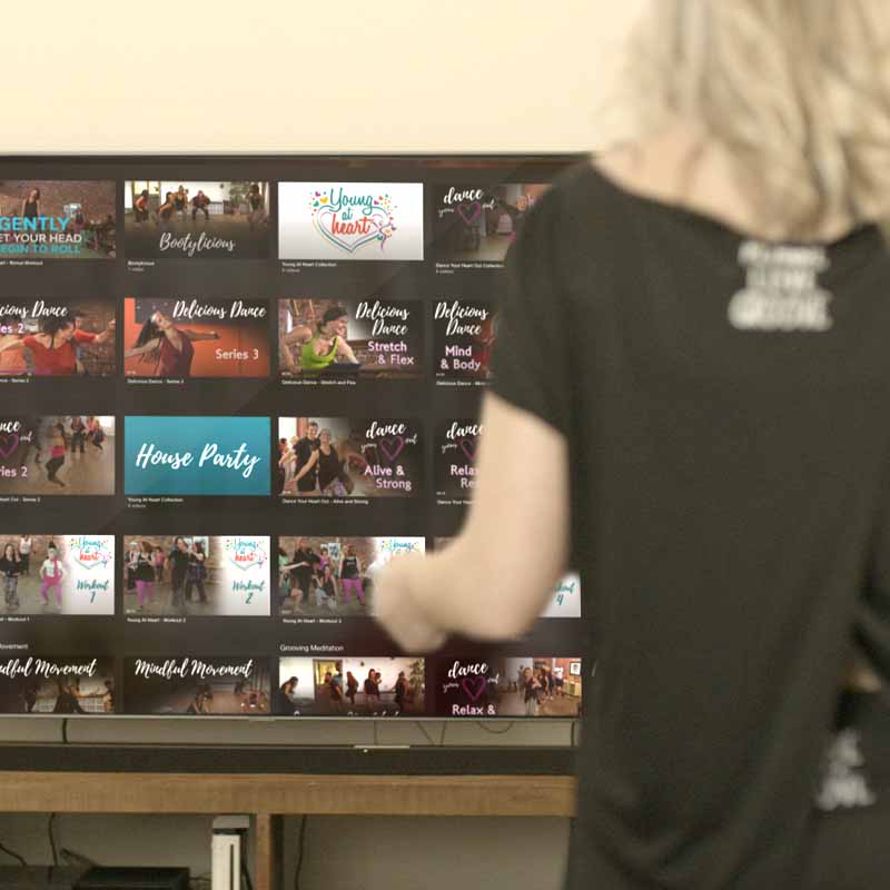 Person browsing dance and fitness videos on a television screen.