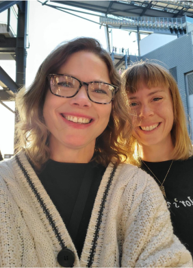 Two smiling women taking a selfie in sunlight.