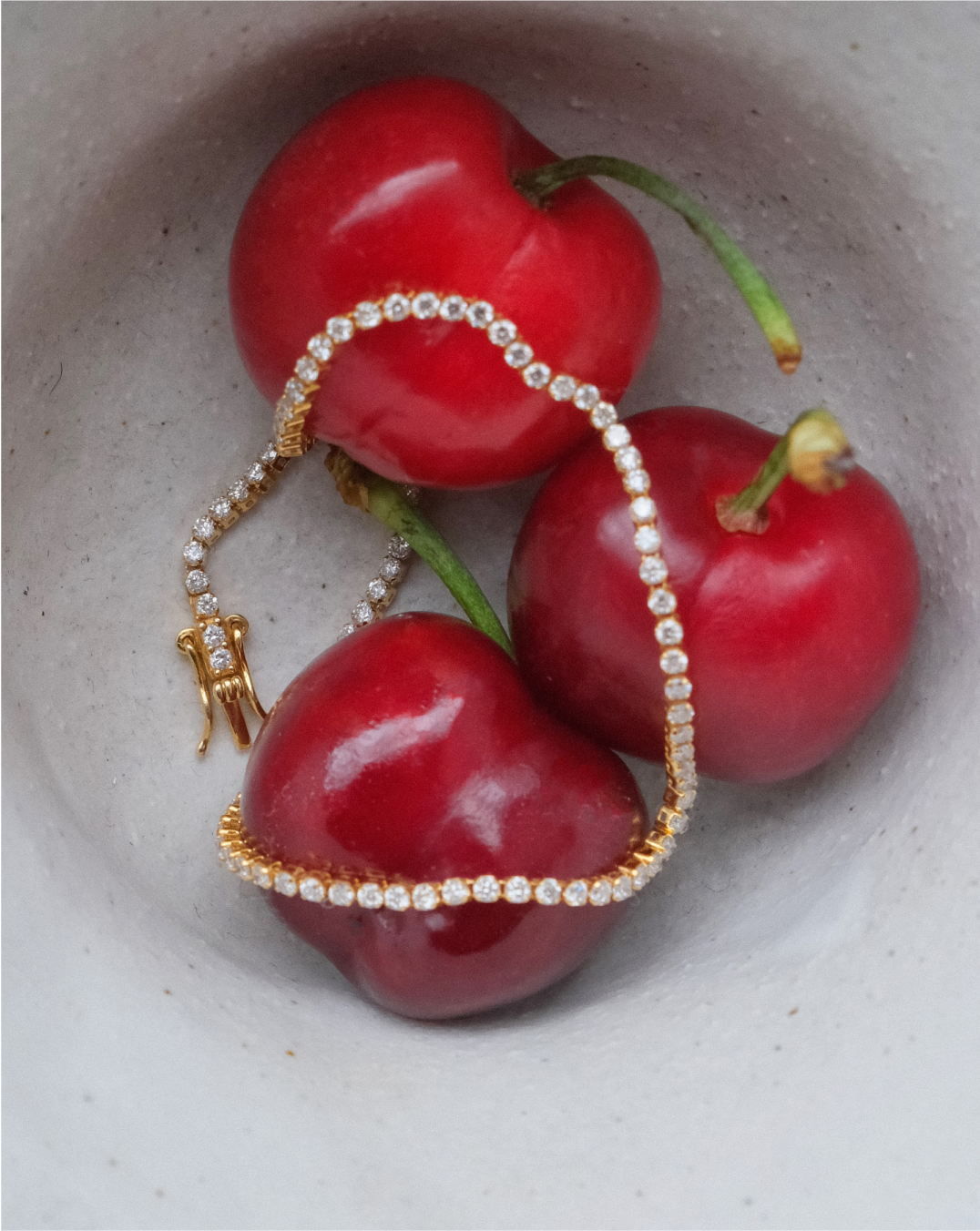 Three cherries adorned with a sparkling diamond bracelet.