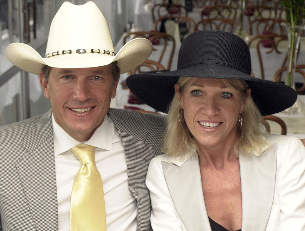 George Strait in a straw cowboy hat with a western hat band with his wife Norma, who wears a women\’s sun hat at the 130th Running of the Kentucky Derby