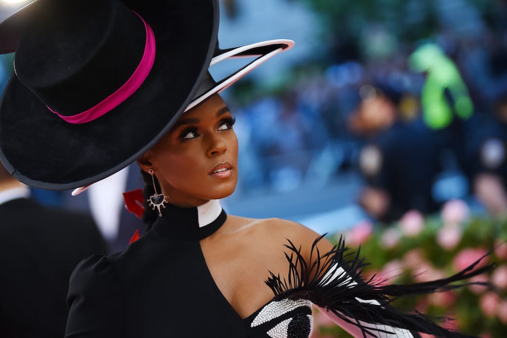 Close up of Janelle Monáe in a four-tiered wide brim hat with a long braid.