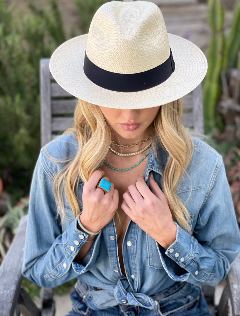 girl with blonde hair sitting in a wood chair outside in a garden wearing a jean shirt, blue jeans and the Afternoon | Straw Fedora by American Hat Makers