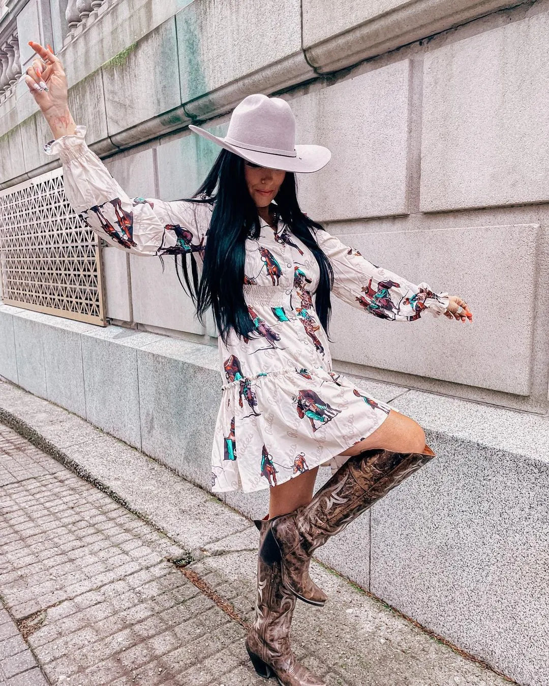 girl in a American Hat Makers felt Cattleman hat in gunsmoke color, wearing a cream colored dress with rodeo print and knee high brown boots with cream stitching