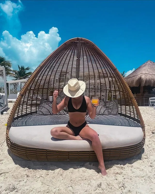 Image of girl in black bikini at the beach sitting on a wicker cabana wearing the Corinth Wide Brim Straw Fedora Hat by American Hat Makers
