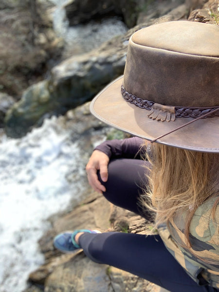 image of Crusher Leather Outback Hat on girl sitting watching a waterfall while on hike