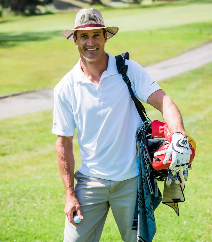 Image of a guy posing while carrying his golf clubs wearing khaki shorts, a white crew t-shirt and the Milan | Straw Fedora Hat by American Hat Makers