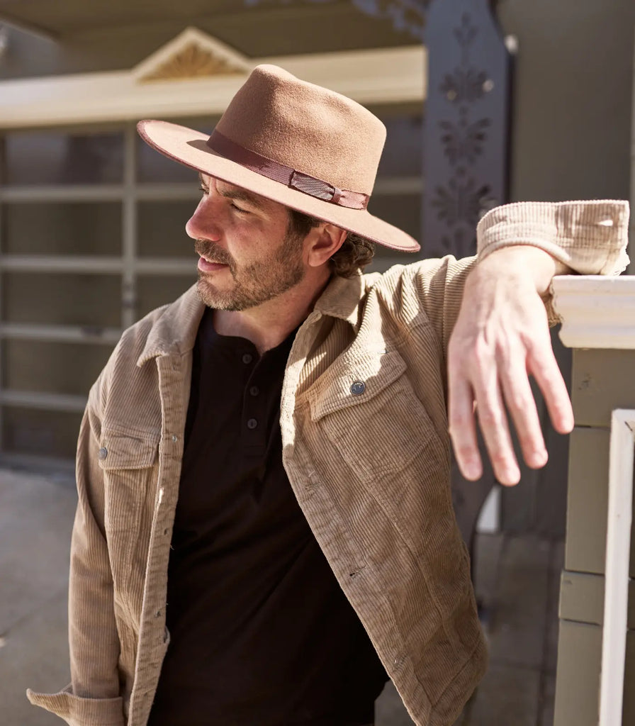 Image of guy leaning on a fence wearing a black shirt, brown jacket and a Bondi | Men's Wide Brim Felt Hat by American Hat Makers (color brown)