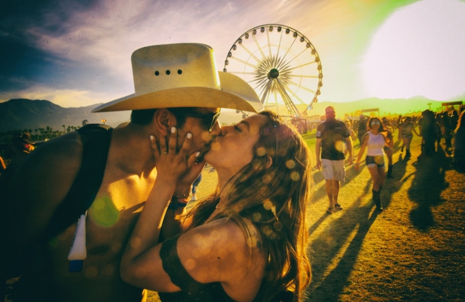 A couple kisses, with the man wearing a white felt cowboy hat