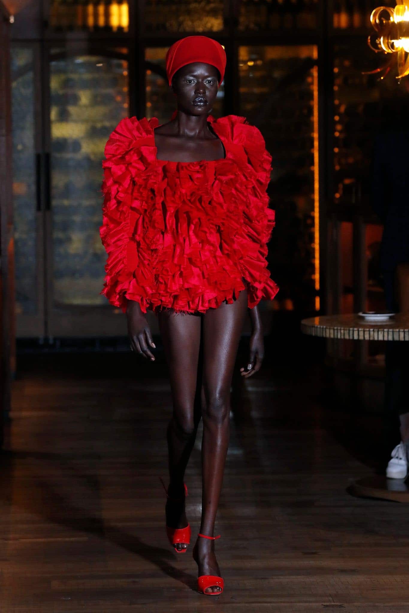 A model walks the runway in a red beanie hat at the Osman show during London Fashion Week September 2021 at The Amazonico