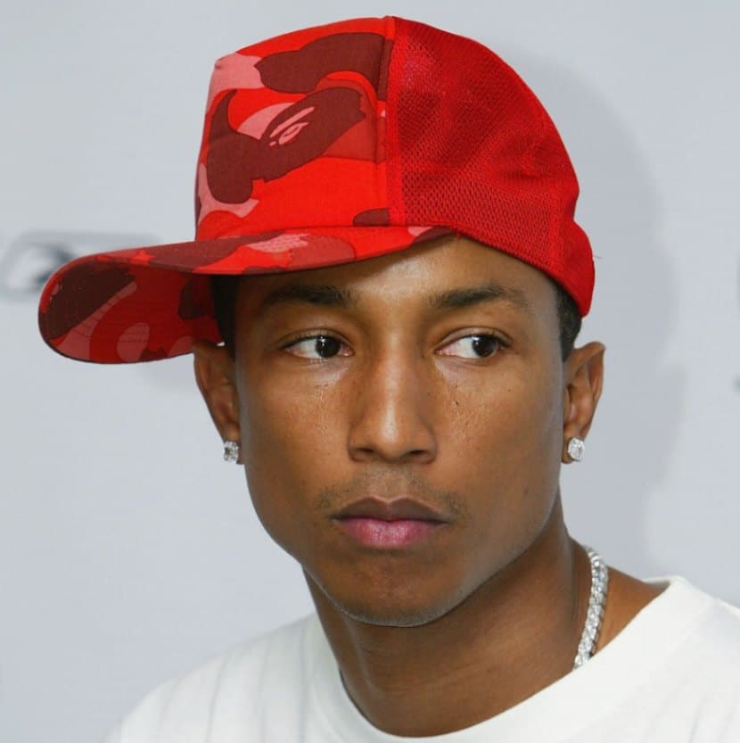 Pharrell Williams wears a camo trucker-style cap at a press conference for Reebok