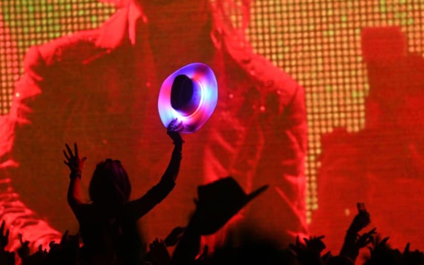 A festivalgoer holds up a neon cowboy hat during a Diplo show