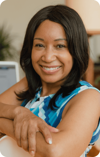 A woman is sitting down and smiling with her arms crossed in front of her..