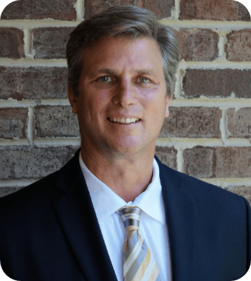 An image of a middle aged man wearing a suit and tie while smiling.