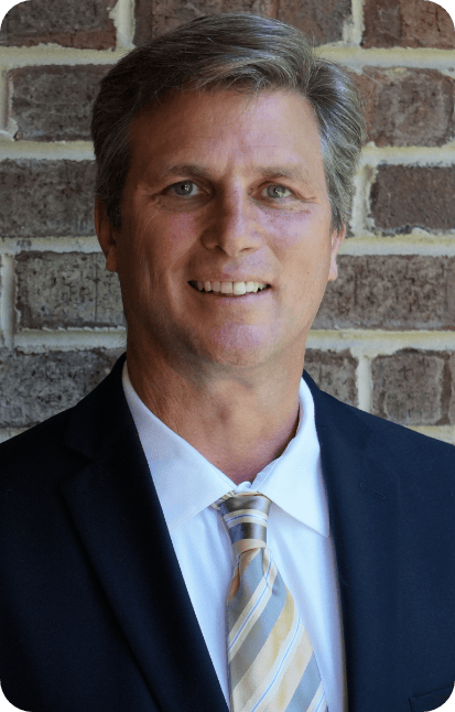 An image of a middle aged man wearing a suit and tie while smiling.