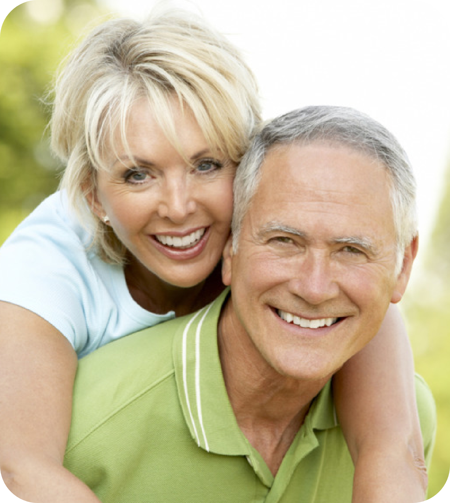 An image of two senior citizens, smiling back at the camera. A senior man is carrying a senior woman on his back.