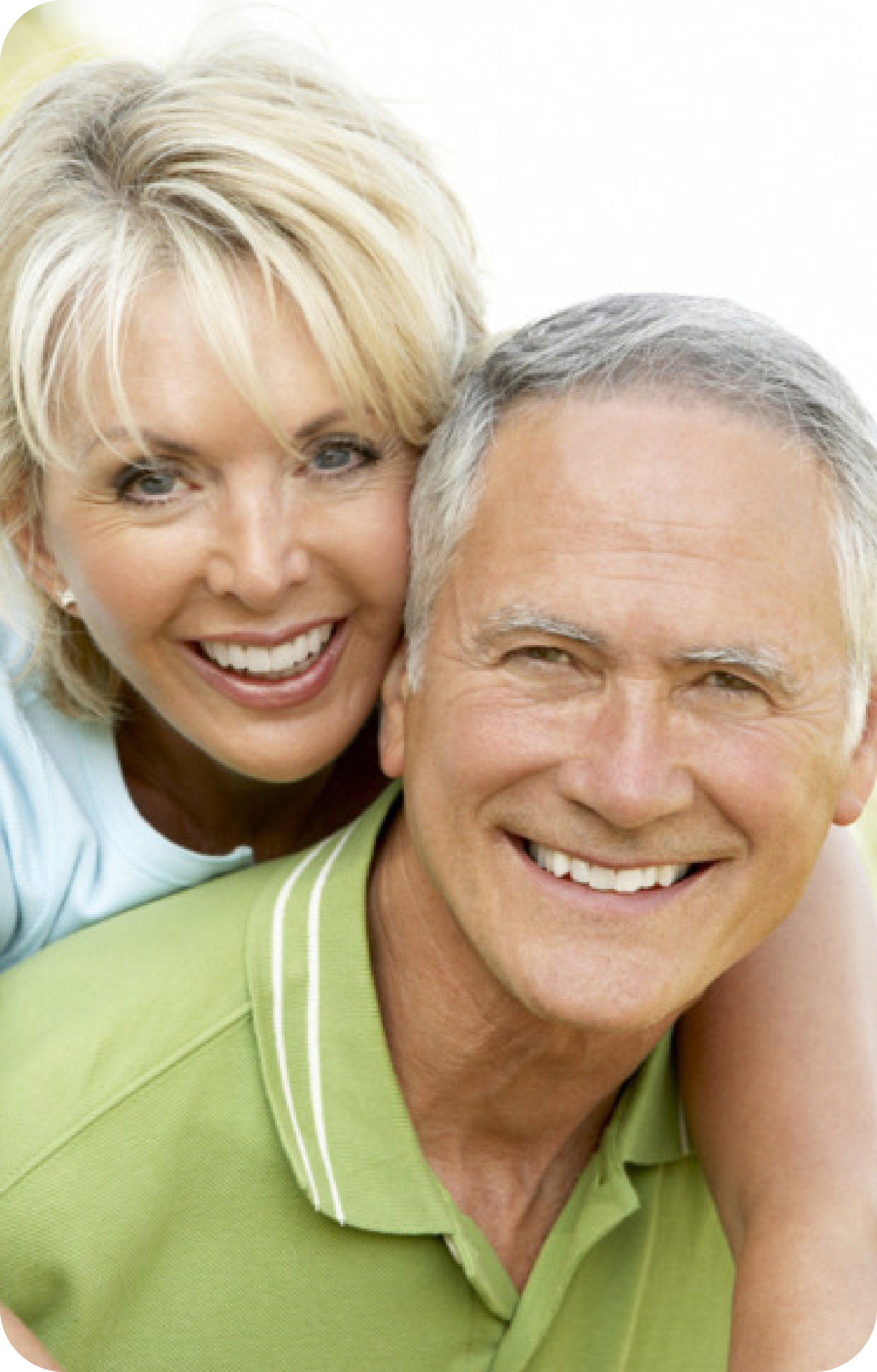 An image of two senior citizens, smiling back at the camera. A senior man is carrying a senior woman on his back.