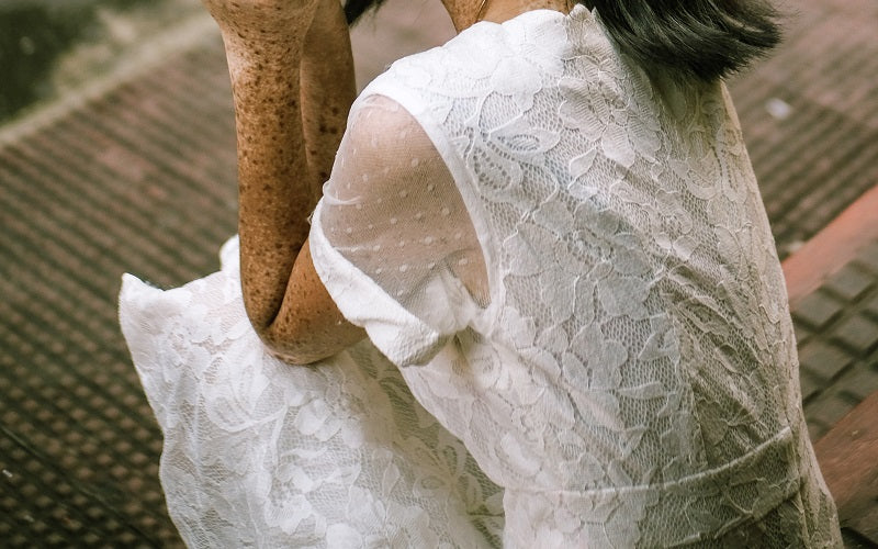 woman in white lace dress sitting on the beach