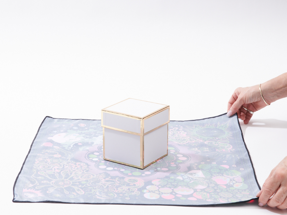 A picture of a gift boxed placed in the centre of a face down furoshiki wrap