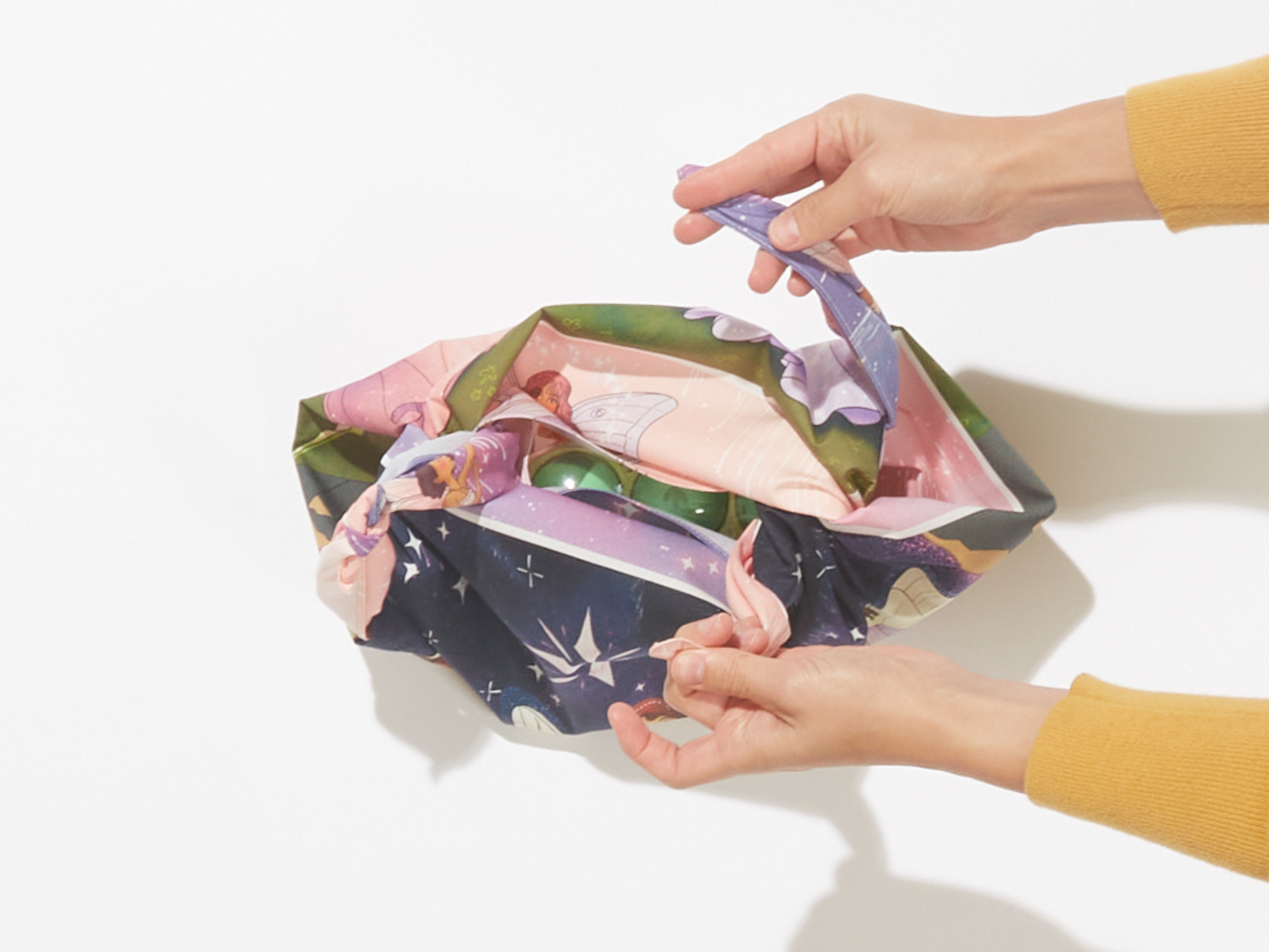 img of someone grabbing the two remaining corners of the furoshiki to create a handle