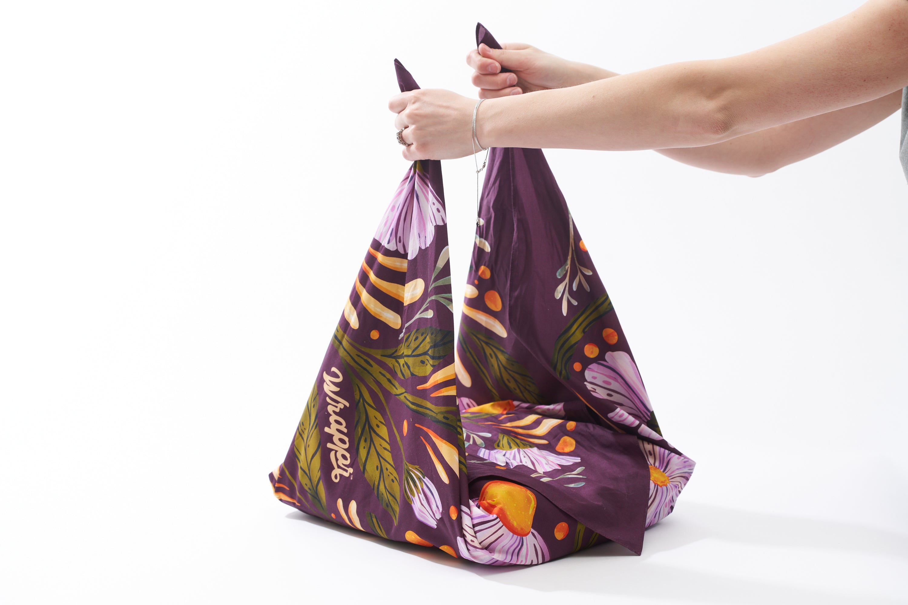 Image of someone grabbing the two opposite corners of a Furoshiki 