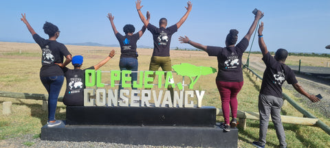 View from the back of people standing near a sign for Ol Pejeta Conservancy 