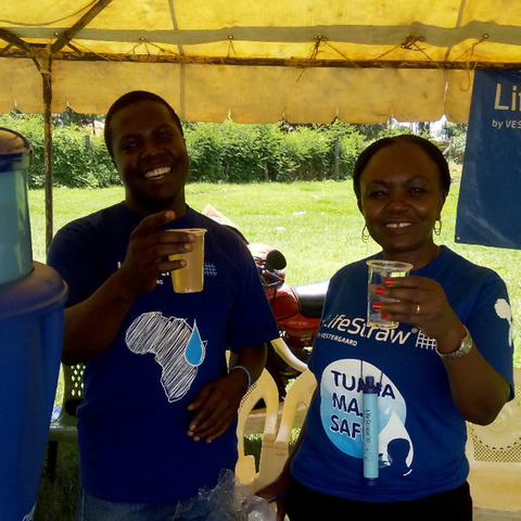 two people holding water next to a LifeStraw community