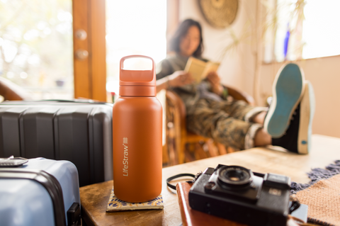 LifeStraw Go Series in the foreground with luggage and a man in soft focus