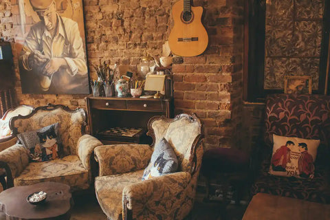 Two armchairs by an exposed brick wall with a guitar hanging
