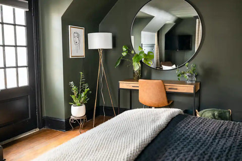 A dark bedroom with plants around the vanity area