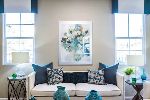 A living room decorated in white and blue like the painting on the wall.