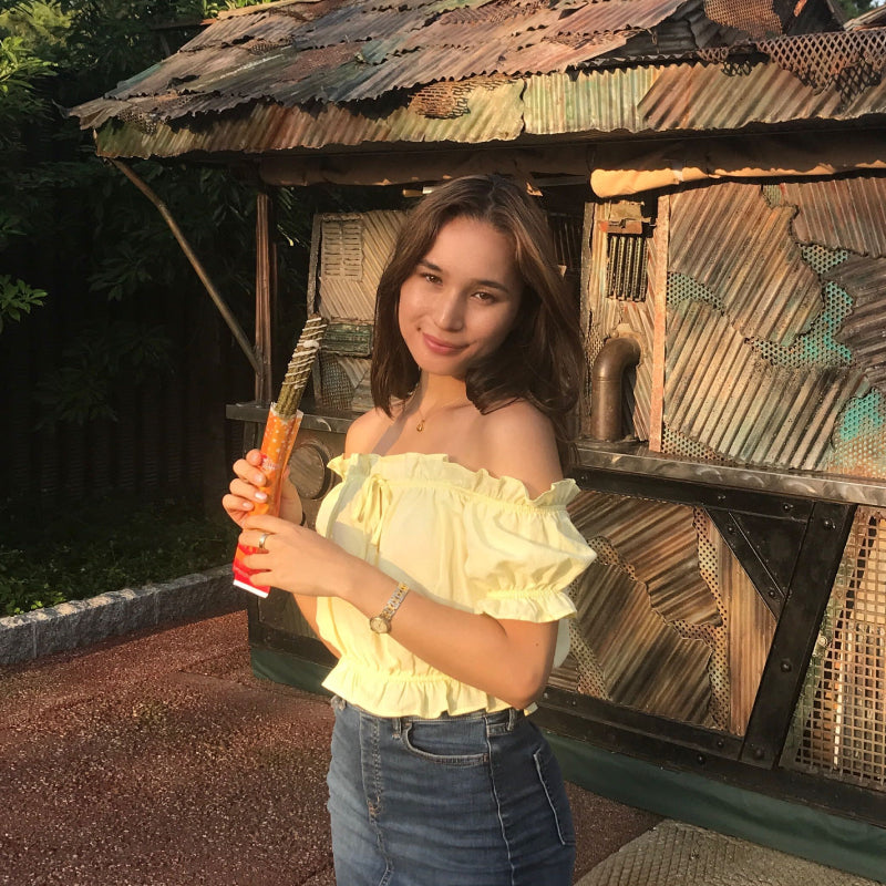 Girl with shoulder length hair, Tami, stands with a churro in hand