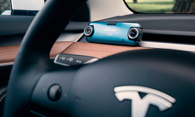 The UltraDash dual-lens dash cam is placed on the Tesla dashboard. In front of the steering wheel is the steering wheel