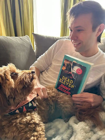 Author Jimmy Juliano with dog Nutmeg, holding his book Dead Eleven