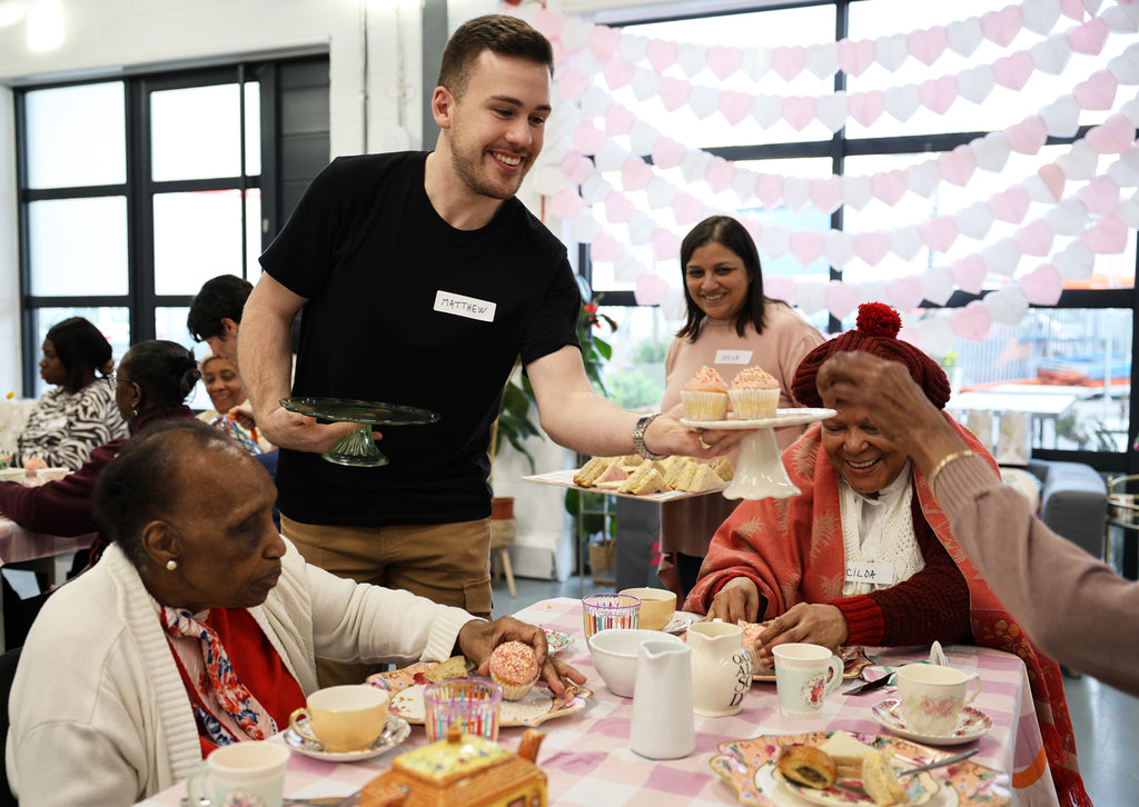 A tea party with Talking Tables staff handing out cake to older people