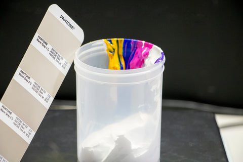 A Pantone book opened to Gray with the ink colors in a container