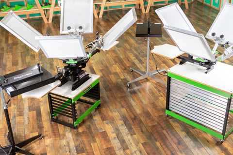 Two screen printing kits sit next to each other on a wood floor