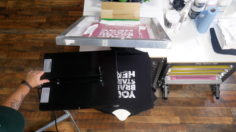 a shirt on a press with a flash dryer and screen nearby