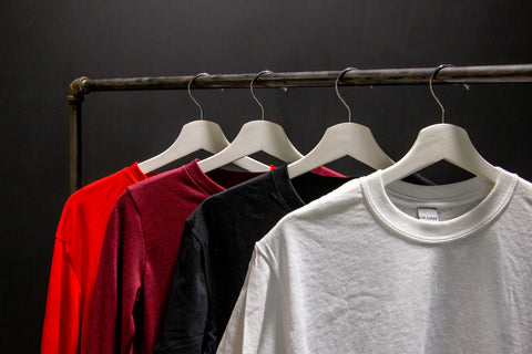 a handful of shirts hang on a rack in front of a black background