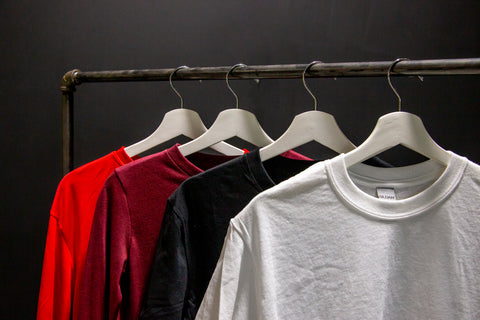 Shirts hang on a rack in front of a black wall
