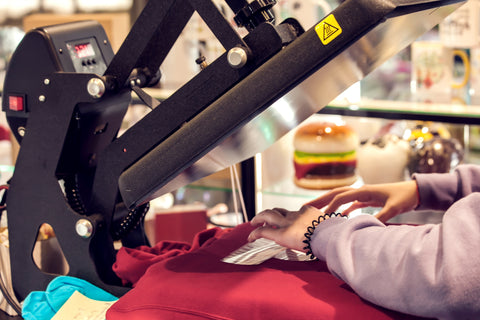 a hand presses a dtf transfer onto a heat press