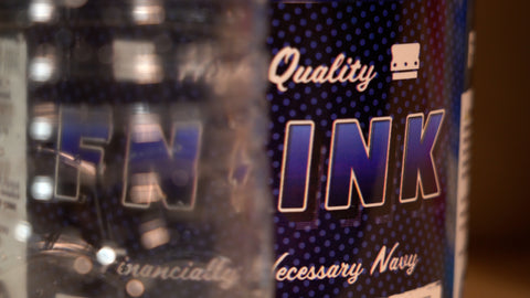 A plastic water bottle in front of a bucket of FN-INK