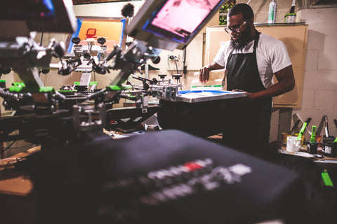 A man stands at his screen printing press