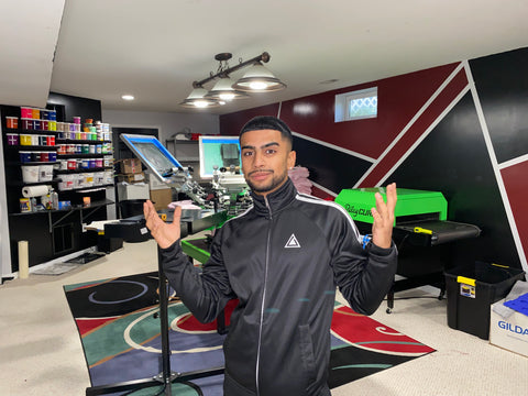 A man in a zip up stands in front of a shop setup