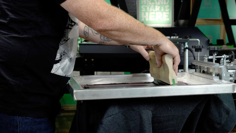 Un hombre imprime una sudadera gris con tinta blanca