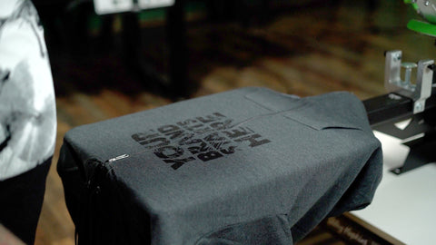 A hoodie printed with black ink sits on a platen