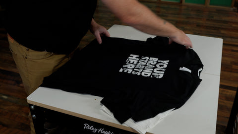 a hand folds black shirts reading "your brand starts here"