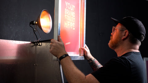 A man holds up a screen to a light to check for proper exposure