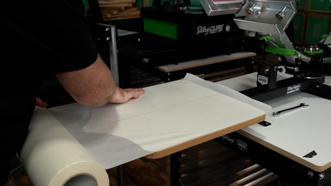 a hand applies platen tape to a platen from a roll of tape