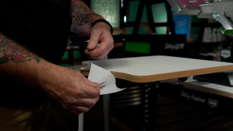 A man holds a piece of paper next to a platen