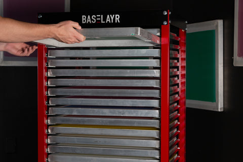 a hand slides a screen into a full baselayr screen rack